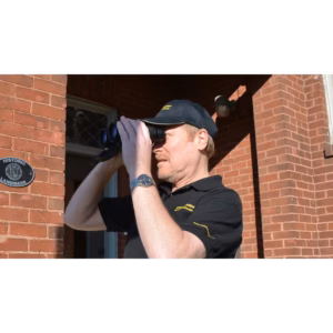 Man looking through binoculars wearing Oberwerk hat