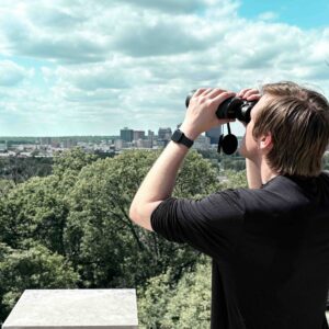 Man viewing a city landscape with the Oberwerk 10x50 Deluxe binocular