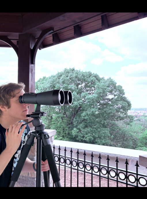Man viewing through the Oberwerk 15x70 Deluxe, mounted on the Oberwerk 3000 Series tripod