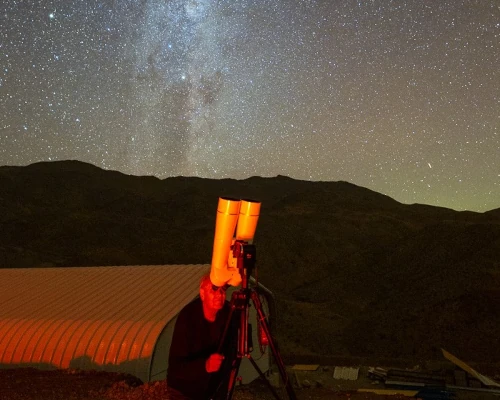 A man looking at the stars with an Oberwerk binocular telescope