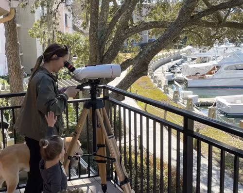 Woman on a balcony looking through an Oberwerk binocular telescope